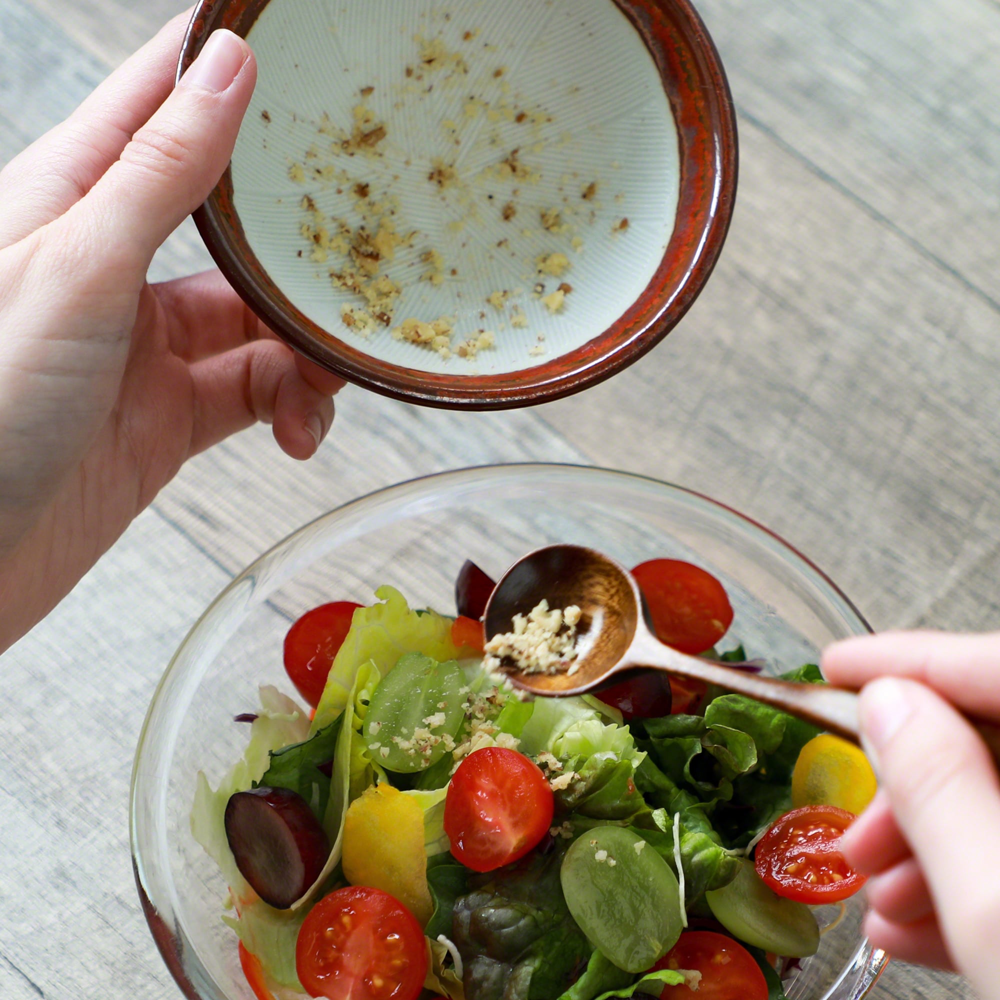 Pouring dressing into a salad from the Asayu Japan Ceramic Red Mortar Bowl.