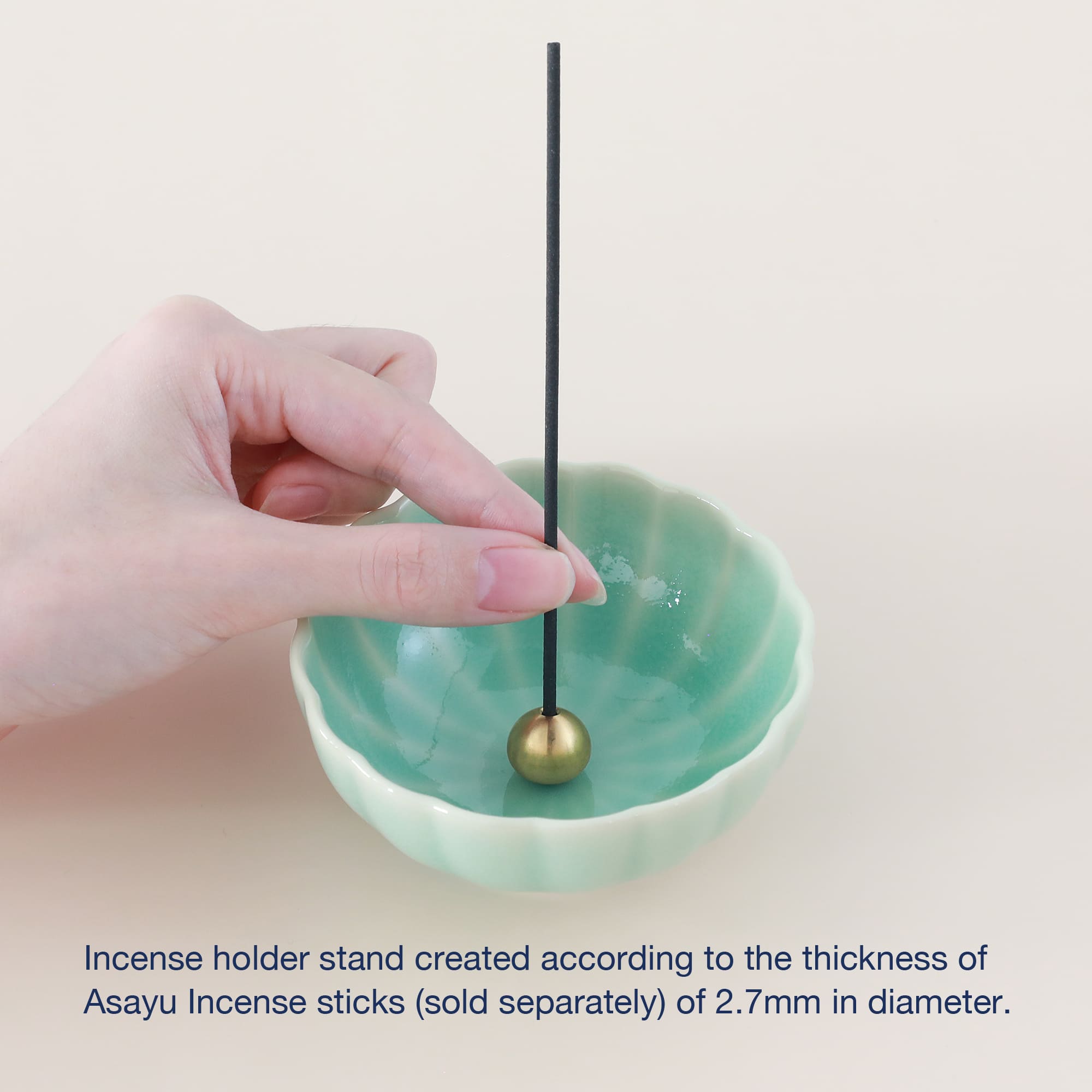 Turquoise ceramic incense holder with brass stand by Asayu Japan with a stick on it.
