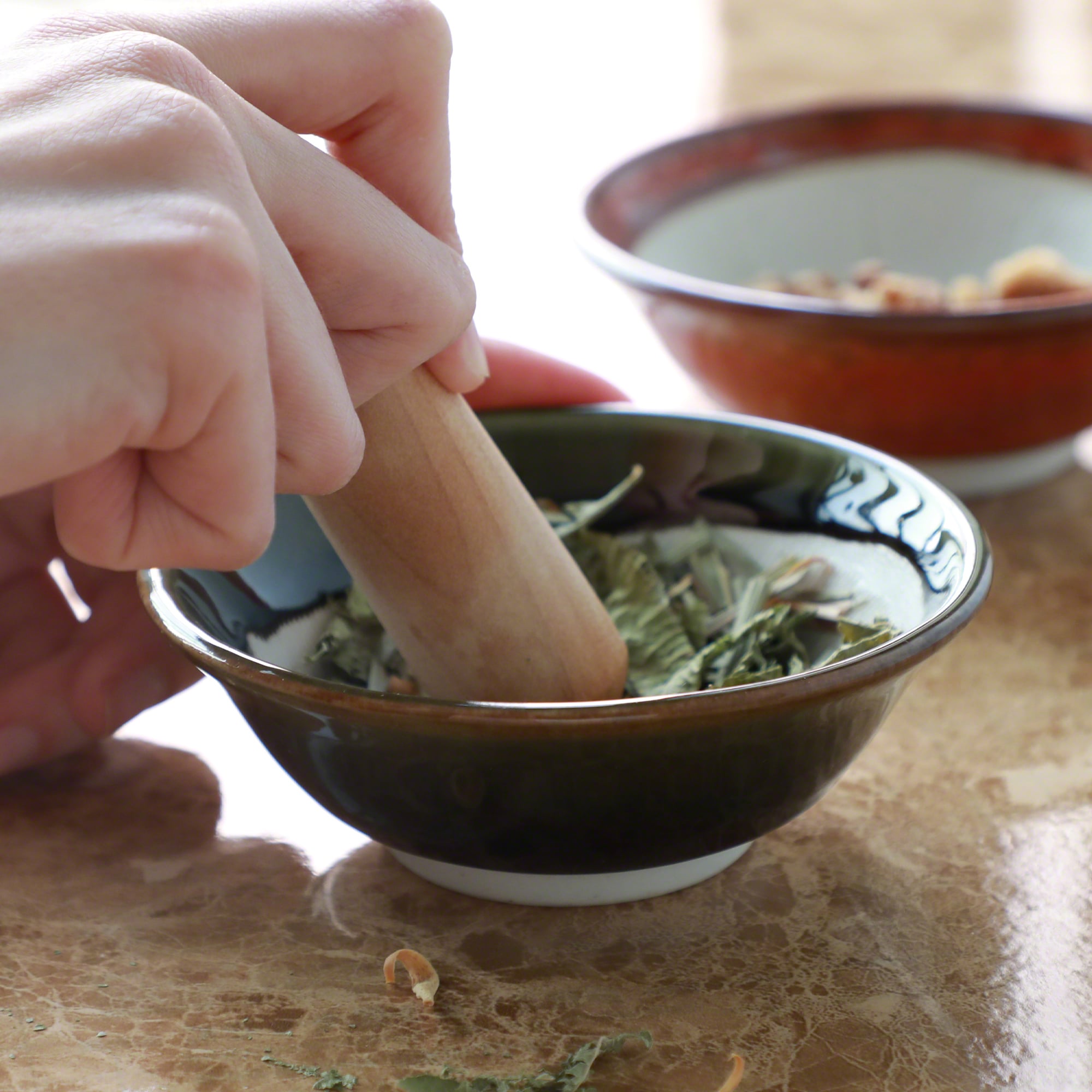 Grinding sage leaves in the the Asayu Japan Olive Green Ceramic Mortar Bowl with the wooden pestle.