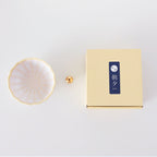 Asayu Japan White and Yellow Mini Lotus Flower Incense Plate next to the included brass incense stand and the packaging box.