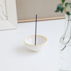  White and Yellow Mini Lotus Incense Holder by Asayu Japan with a stick in a desk.