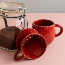 Load image into Gallery viewer, The Asayu Japan Coffee Dripper in chrome red on the side next to the matching accessory mug and a glass container with ground coffee.
