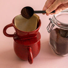 Load image into Gallery viewer, Pouring ground coffee inside the paper filter on the Asayu Japan Coffee Dripper in Chrome Red to prepare pour over coffee.
