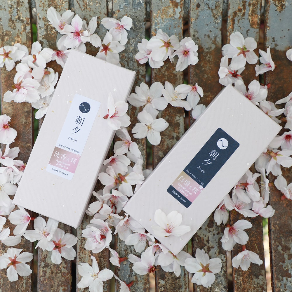 A box of Premium Sakura Cherry Blossom and Agarwood and a box of Premium Sakura Cherry Blossom and Sandalwood Incense Sticks by Asayu Japan surrounded by sakura petals