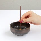 hand placing an incense stick in zen incense holder 