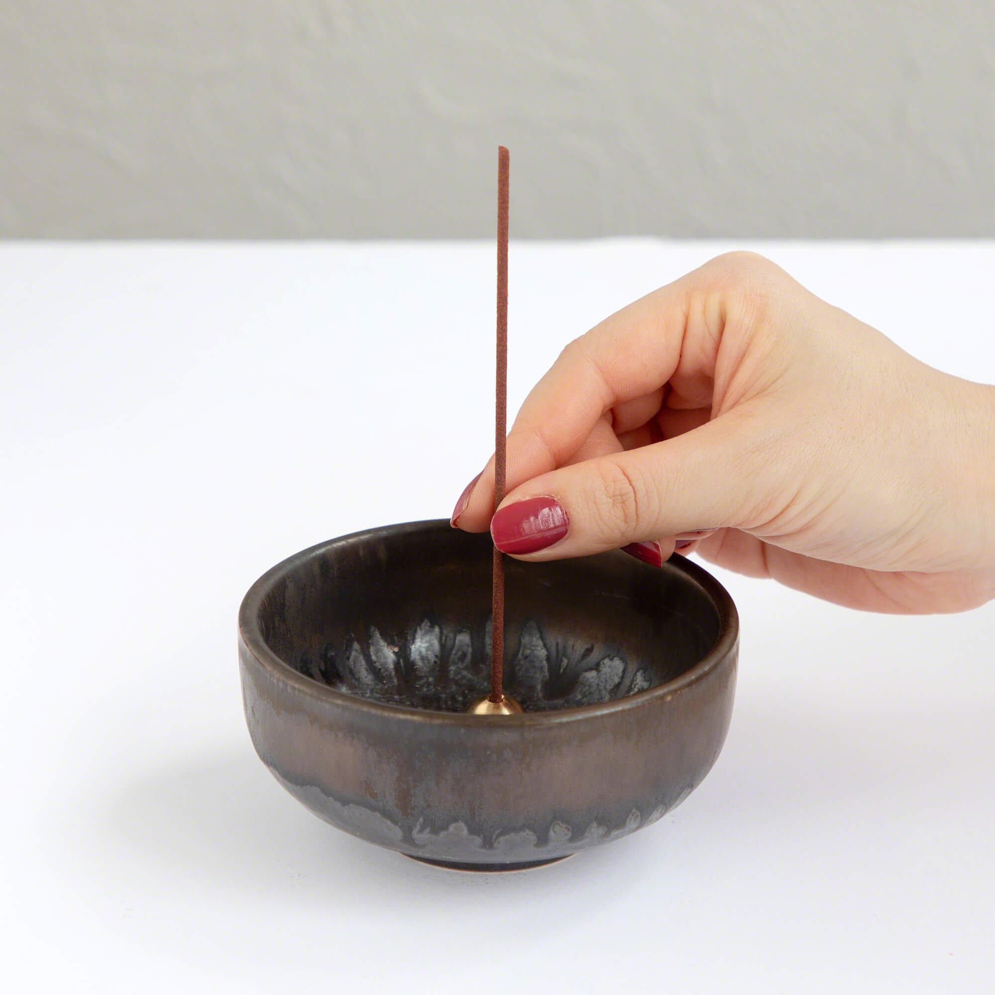 hand placing an incense stick in zen incense holder 